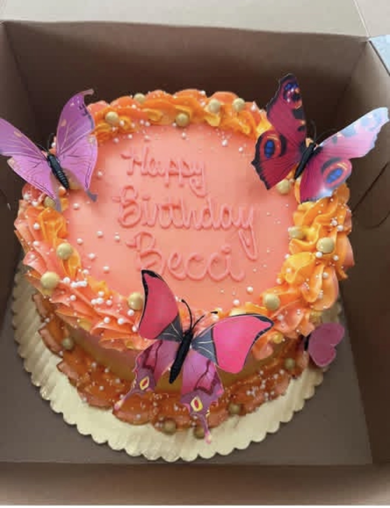 Orange and pink birthday cake with edible butterflies and buttercream ruffles